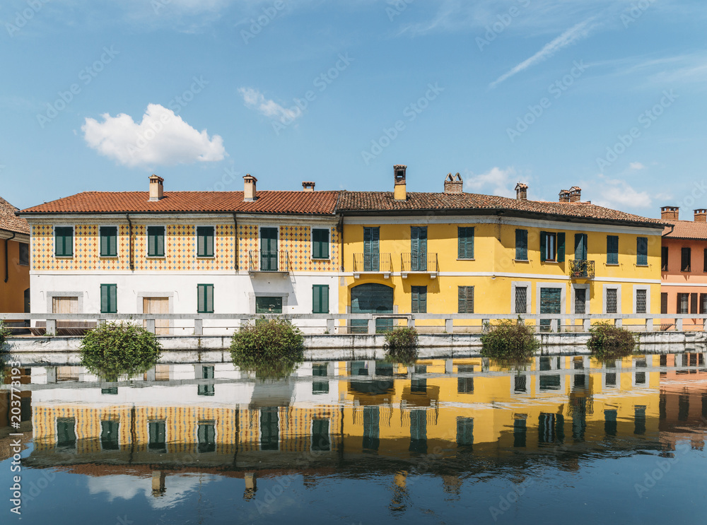 Cityscape of Gaggiano, just outside of Milan. Colourful houses reflected in the Naviglio Grande canal waterway