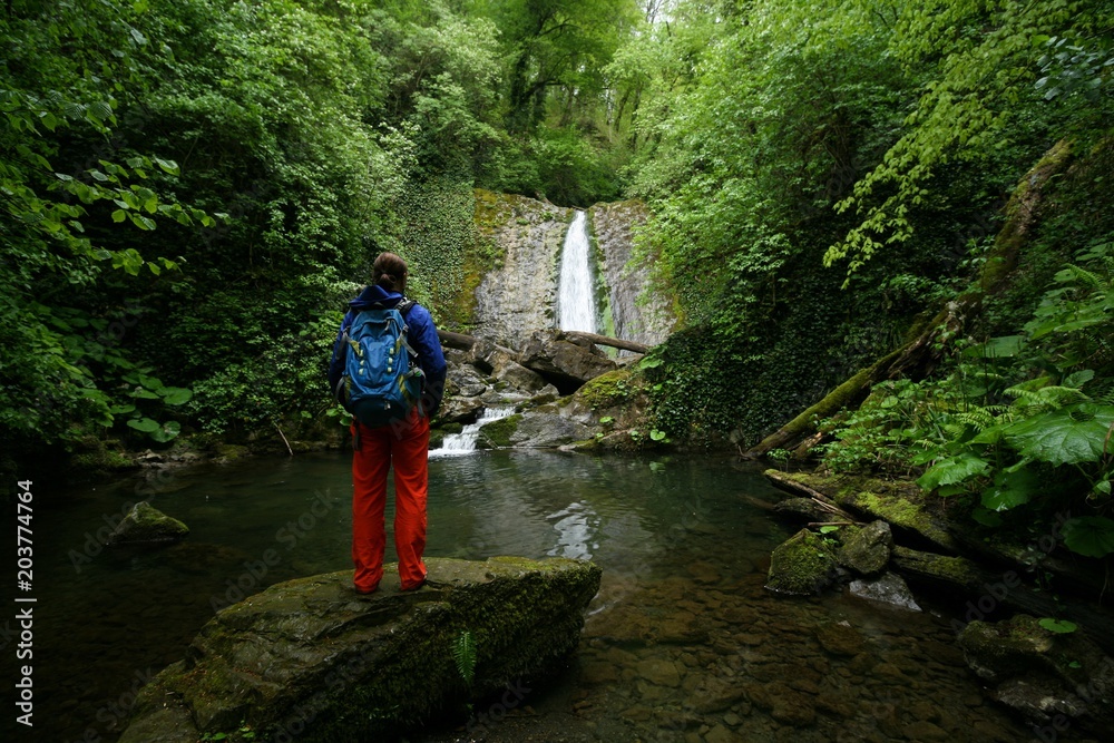 Tourist admires the waterfall in the forests of Sochi Tourist admires the waterfall in the forests of Sochi