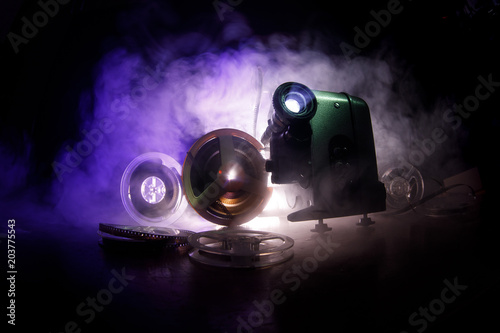 Old style movie projector, close-up. Film projector on a wooden background with dramatic lighting and selective focus. Movies and entertainment concept