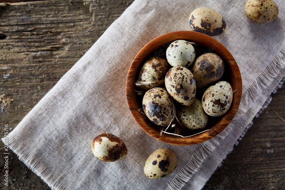 Bowl with eggs quail, eggs on a homespun napkin, boxwood on wooden background, close-up, selective focus Bowl with eggs quail, eggs on a homespun napkin, boxwood on wooden background, close-up, selective focus