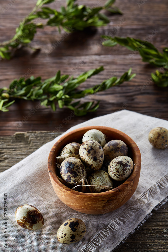 Bowl with eggs quail, eggs on a homespun napkin, boxwood on wooden background, close-up, selective focus Bowl with eggs quail, eggs on a homespun napkin, boxwood on wooden background, close-up, selective focus