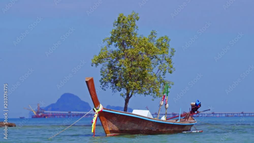 View seaside in sunny day of a long-tail boat floating in the blue-green sea near by the tree on white sand beach with many cloud and blue sky background, Adang island, Stun, Thailand View seaside in sunny day of a long-tail boat floating in the blue-green sea near by the tree on white sand beach with many cloud and blue sky background, Adang island, Stun, Thailand