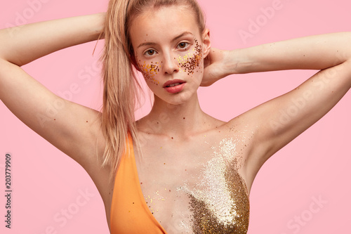 Lovely young female model with appealing appearance, poses at camera for cove...