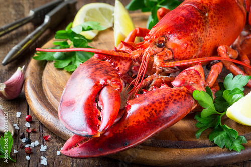 Steamed red lobster on a wooden cutting board with parsley and lemon