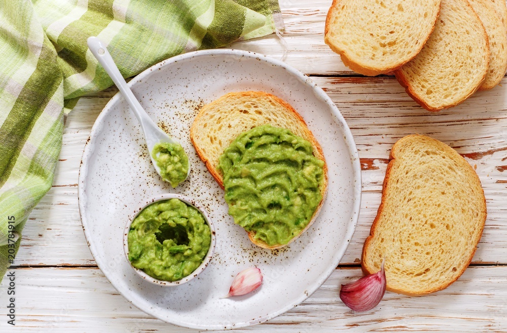 Traditional Latinamerican mexican guacamole sauce and avocado sandwiches on light wooden background Traditional Latinamerican mexican guacamole sauce and avocado sandwiches on light wooden background