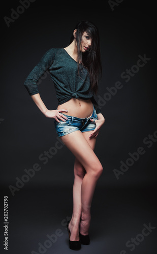 Studio fashion shot: portrait of seductive young girl in denim shorts and blouse. Model test