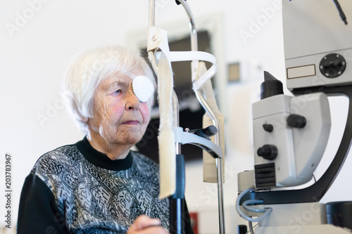 Elderly 95 years old woman wearing eye pathc after laser surgery procedure at ophthalmology clinic. Age, vision, surgery, eyesight and people concept. photo