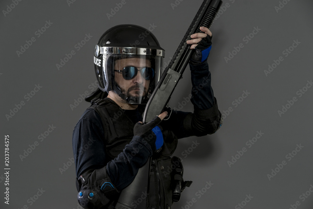 Guard policeman with full equipment for anti-riot, Law enforcer in protective uniform ready for crowd control isolated on black Guard policeman with full equipment for anti-riot, Law enforcer in protective uniform ready for crowd control isolated on black
