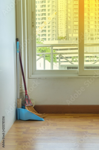 dustpan and sweeping broom on wooden floor
