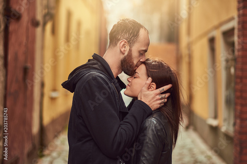 Bearded man and brunette girl kissing, on the background of the old European street. © Fxquadro