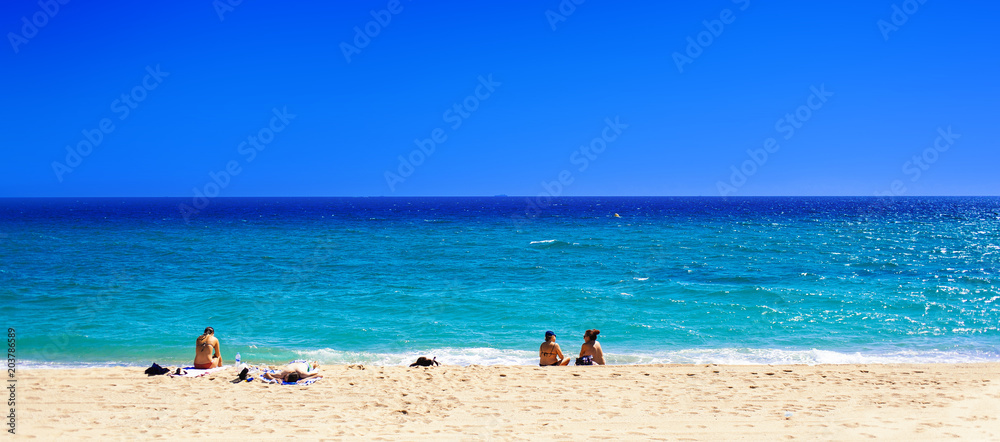 Summer beach with people taking sunbath on golden sand. Not crowded beach.   Summer Holiday Concept with blue sea