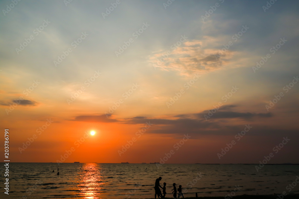 silhouette man and children play on beach and sunset