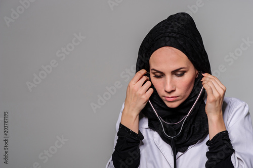 Arab female doctor posing and smiling isolated on a grey background.