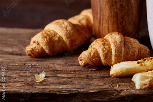 Puff pastries on piece of board over dark wooden table, close-up, selective focus, backlight.