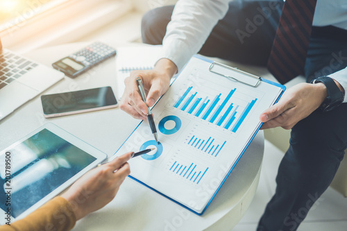 Two business point a pen to each other above chart report at meeting or negotiation in the office.