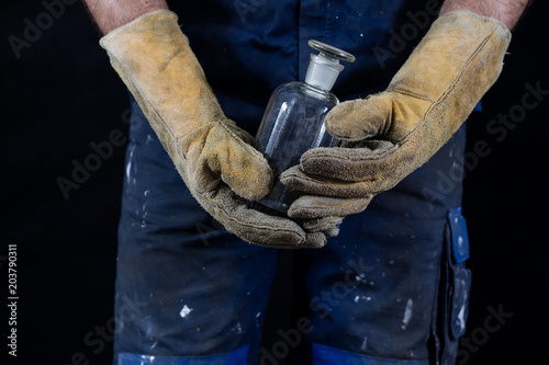 Hazardous materials and acids. Acid bottle kept in gloves by a construction worker.