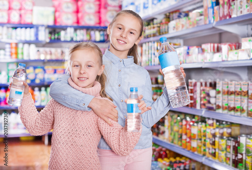 Little girls in supermarket with bottled water