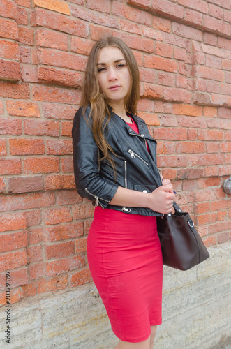 girl in dress and leather jacket on brick wall background