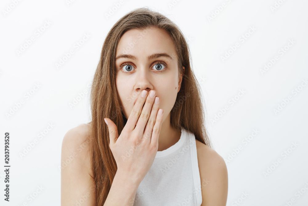 No way, tell me details. Shocked impressed attractive woman with fair hair, covering mouth with palm and staring amazed at camera, being astonished with gossip or rumor over gray background No way, tell me details. Shocked impressed attractive woman with fair hair, covering mouth with palm and staring amazed at camera, being astonished with gossip or rumor over gray background