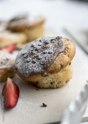 A delicious, freshly baked chocolate covered chocolate chip muffin frosted or spinkled with icing sugar on a business breakfast buffet in the UK