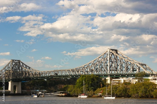 Story Bridge above Brisbane River with sailboats on cloudy day, Queensland, Australia