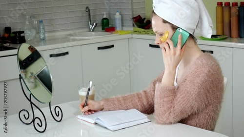 attractive business woman applying cosmetic facial spots at home, talking on the phone photo