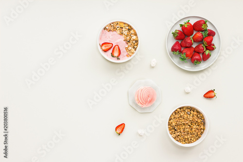 Healthy breakfast with yogurt, muesli, fruits, strawberry on grey background, flat lay, top view