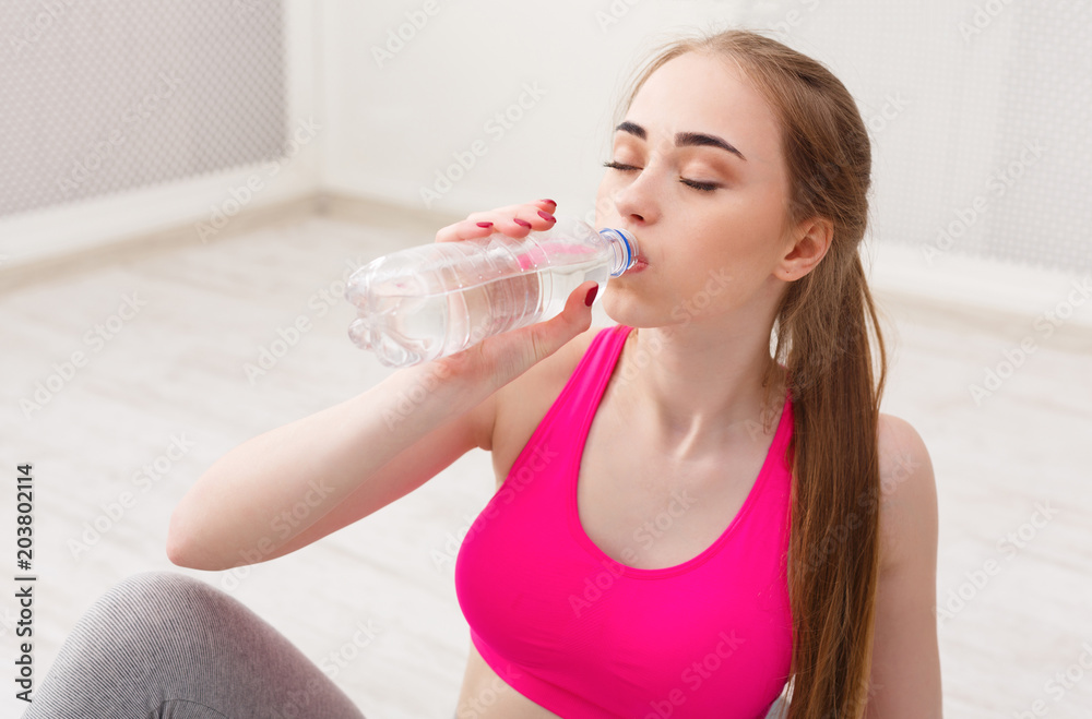 Fitness woman drinking water at gym on white background Fitness woman drinking water at gym on white background