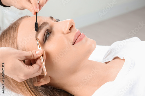 Young woman having professional eyebrow correction procedure in beauty salon © New Africa