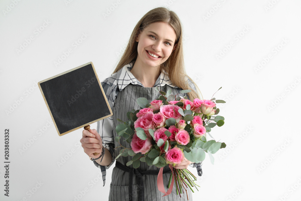 Female florist holding small chalkboard and bouquet on light background Female florist holding small chalkboard and bouquet on light background