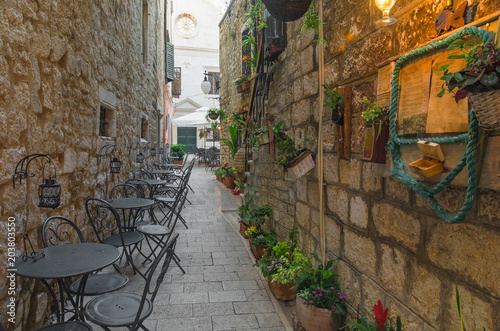 Cafe tables and chairs outside in old cozy street in Split, Croatia