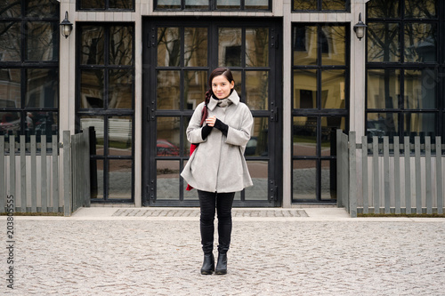 Asian girl walking at the street dressed in gray coat during springtime