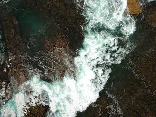 Aerial view of sea waves crash on the rocks in the coastline