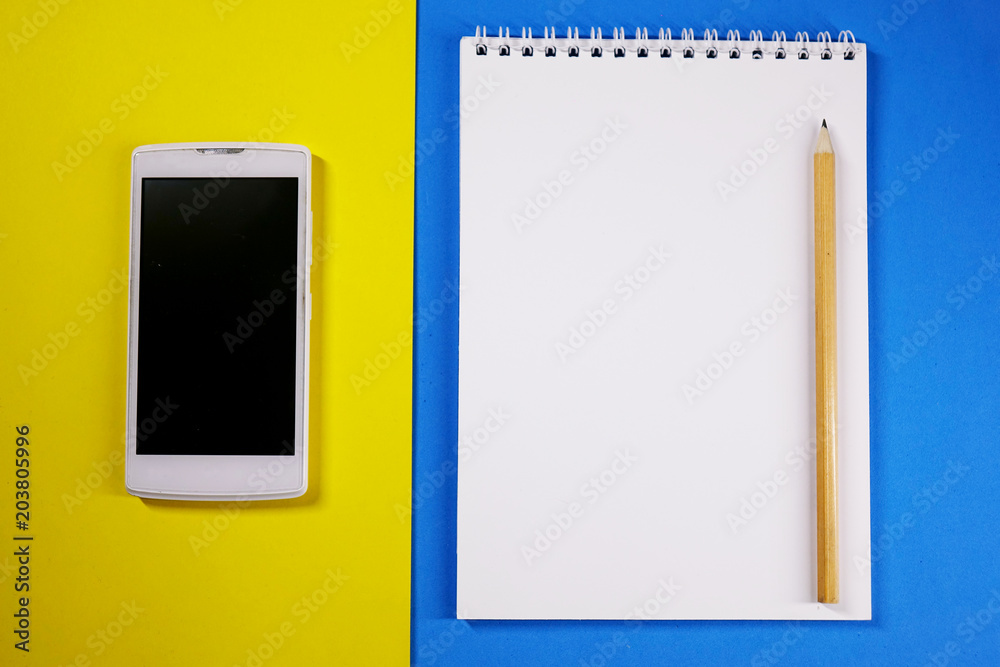 Notepad, pencil and phone on colored background top view, school, business, education Notepad, pencil and phone on colored background top view, school, business, education