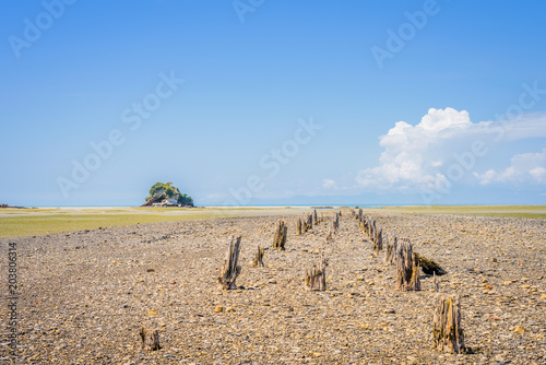 Farewell Spit, Golden Bay, New Zealand: Low Tide coastal bay landscape at the north west cape of south island with a small cliff rock and green grass and blue ocean sea near Abel Tasman National Park photo