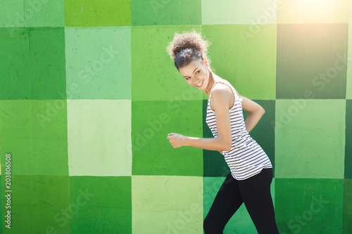 Side view of woman running against bright wall photo
