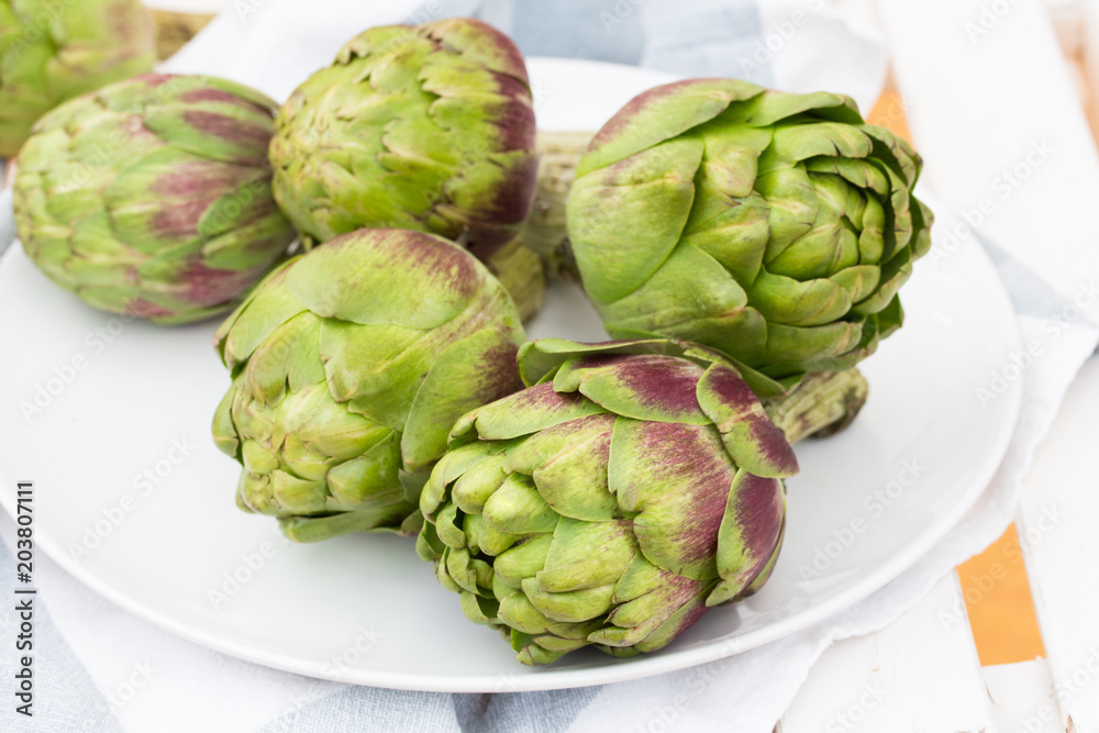 fresh artichokes on rustic wooden chair fresh artichokes on rustic wooden chair
