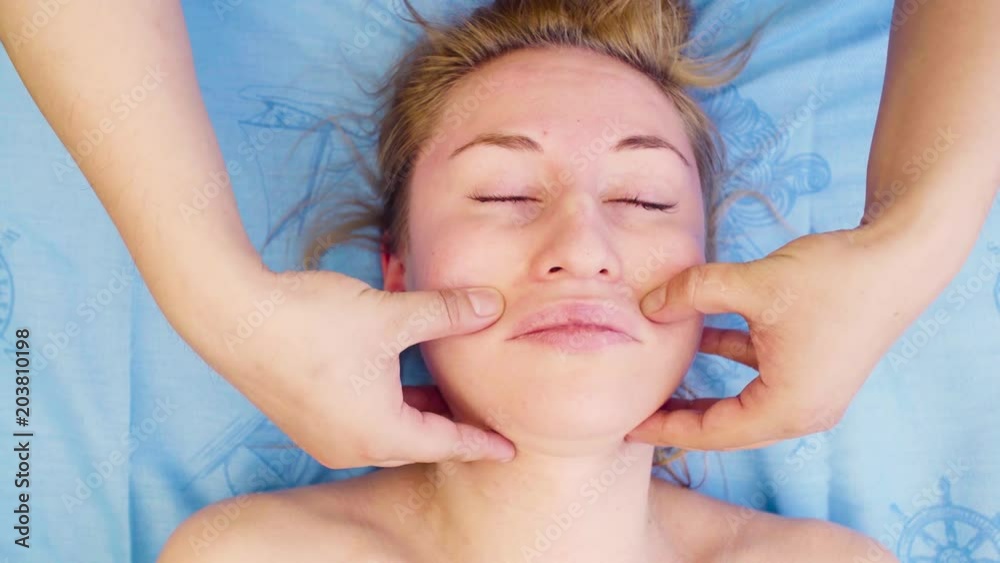 Top view. Close up hands of professional massage therapist doing massage of the woman's face