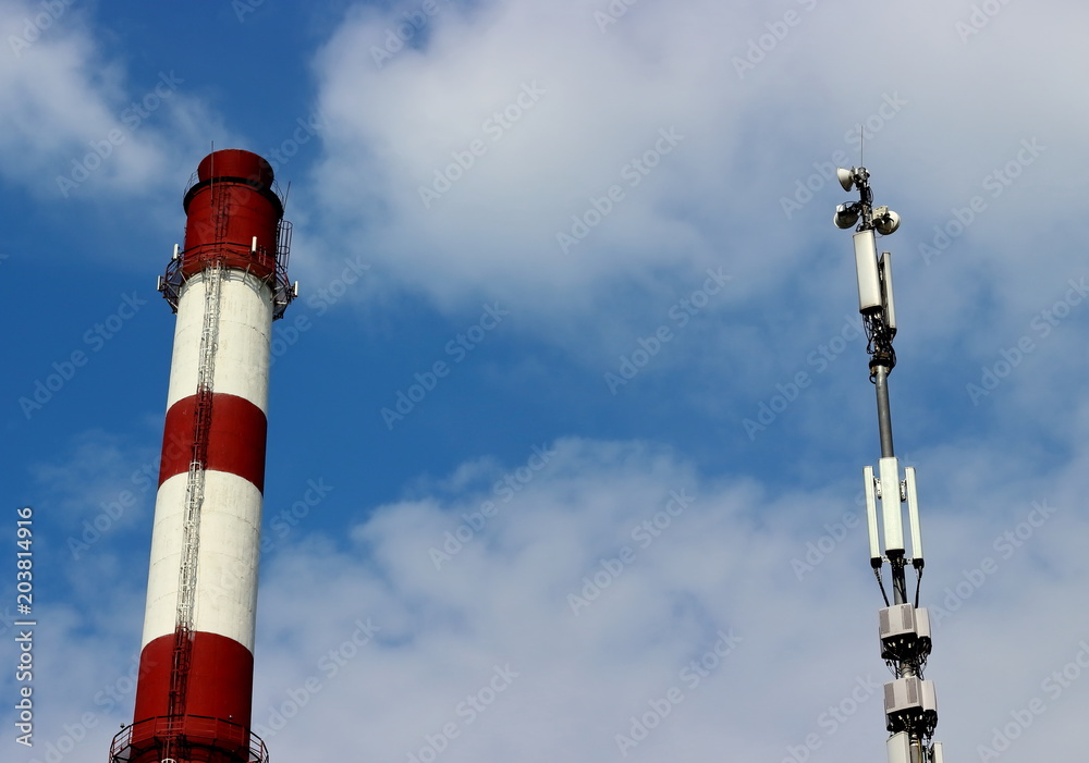 Boiler pipe with red and white stripes and loudspeaker warning system against on a blue sky with clouds. Copy space for text. Boiler pipe with red and white stripes and loudspeaker warning system against on a blue sky with clouds. Copy space for text.