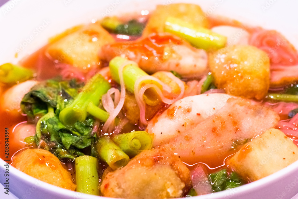 Thai food.Pink seafood flat noodles.Spicy lemongrass flavored soup with pork, chicken on background.Close up Thai food.Pink seafood flat noodles.Spicy lemongrass flavored soup with pork, chicken on background.Close up
