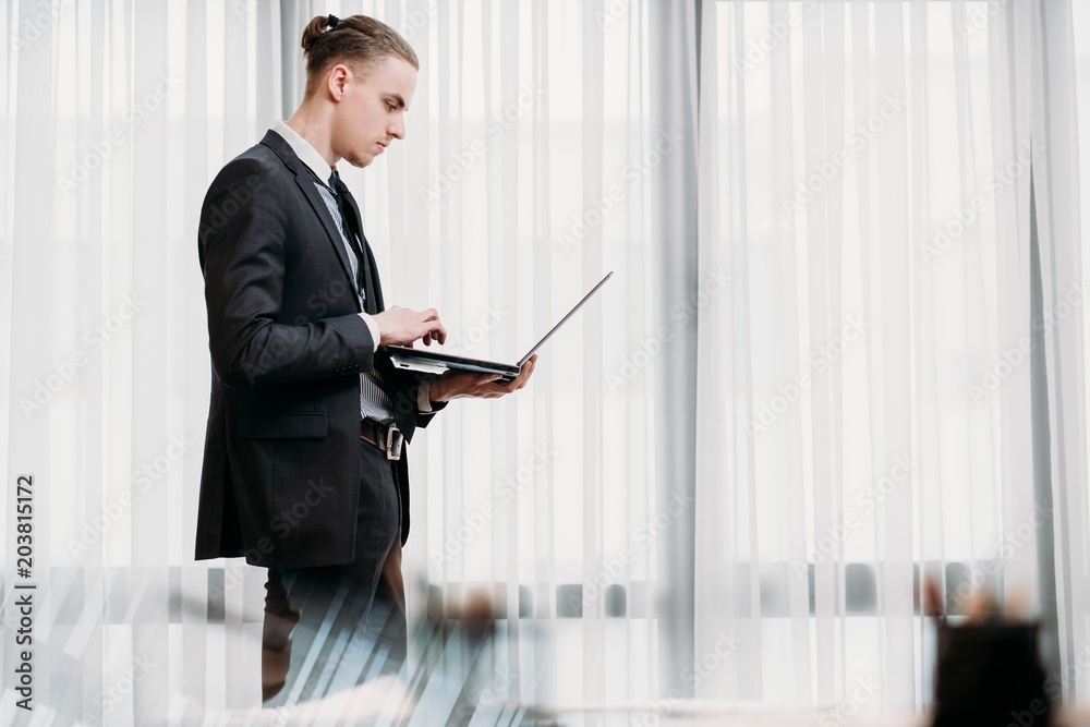 Fototapeta premium business man reading documents on laptop in his office. stylish young handsome executive at work