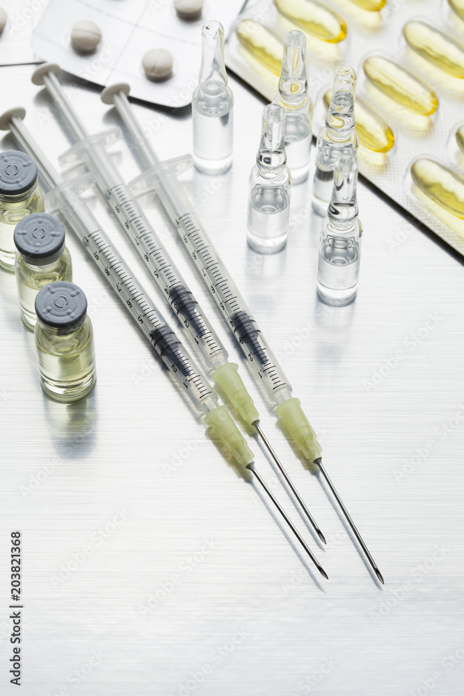 Various medications as injections and tablets on a shiny steel background Various medications as injections and tablets on a shiny steel background