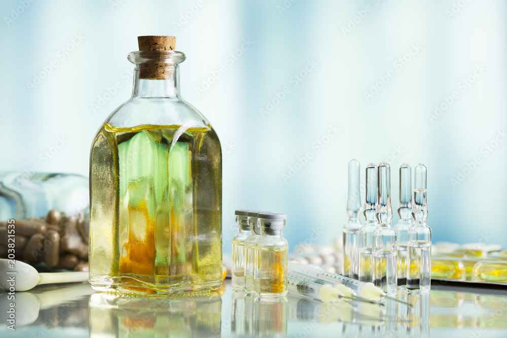 Medical syrup in a glass bottle, pills and injections on a blue background Medical syrup in a glass bottle, pills and injections on a blue background