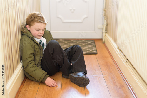Schoolboy sat by front door, unhappy and sad about going to school © Stephen Davies