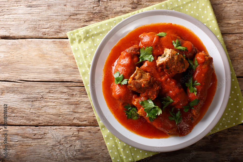 Italian food: beef steak stuffed with parsley and parmesan cheese in tomato sauce close-up on a plate. horizontal top view Italian food: beef steak stuffed with parsley and parmesan cheese in tomato sauce close-up on a plate. horizontal top view