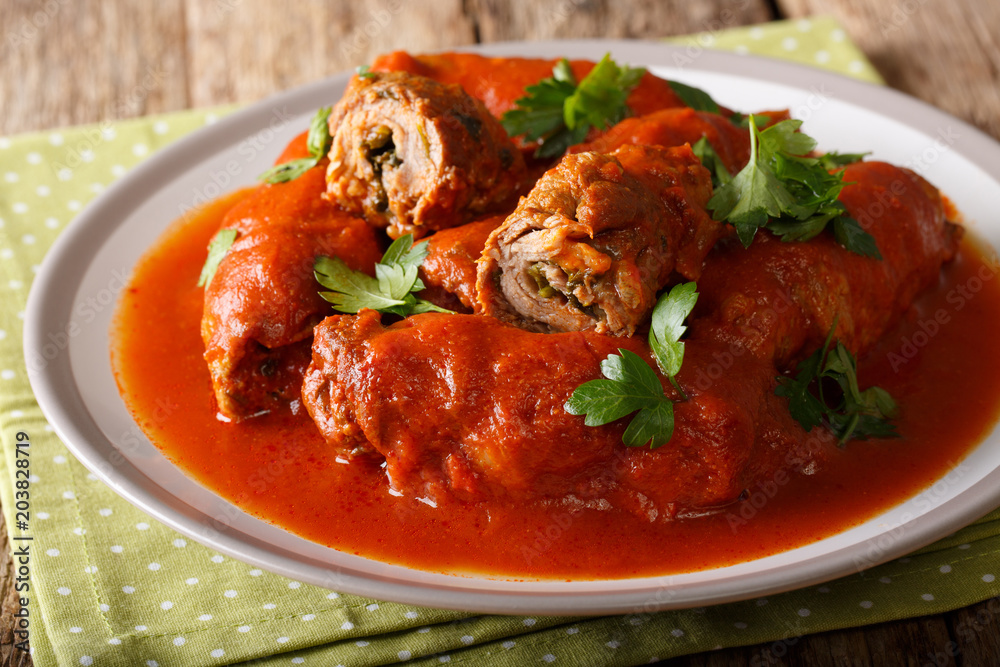 Delicious beef steak stuffed with parsley and parmesan cheese stewed in tomato sauce close-up. horizontal Delicious beef steak stuffed with parsley and parmesan cheese stewed in tomato sauce close-up. horizontal