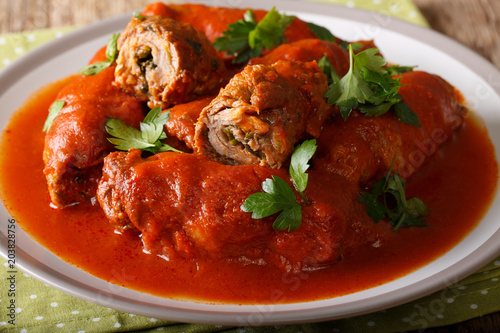 Beef roll stuffed with parsley and cheese stewed in tomato sauce close-up. horizontal photo