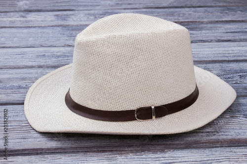 White straw hat with belt. Wooden desk surface background.