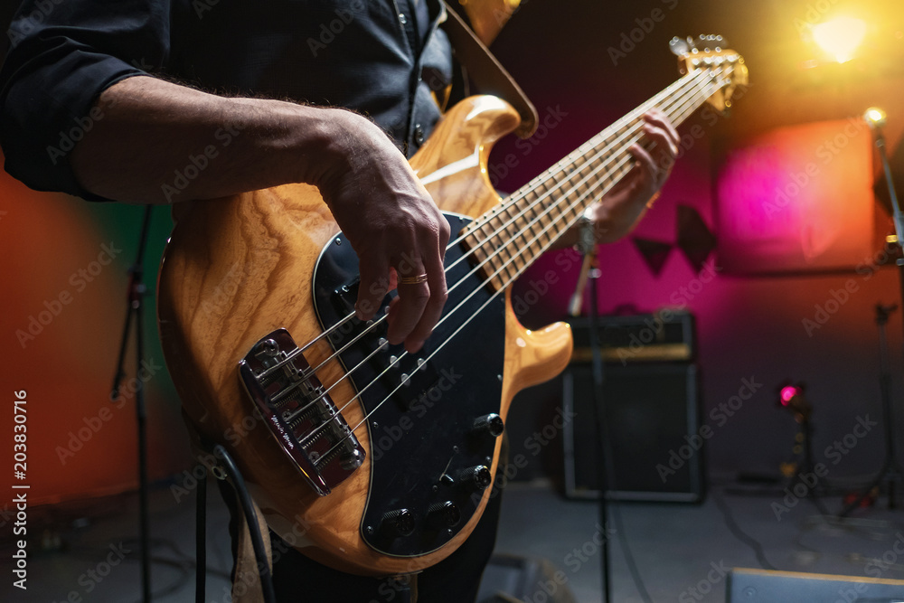bass guitar in the hands of a musician - obrazy, fototapety, plakaty 