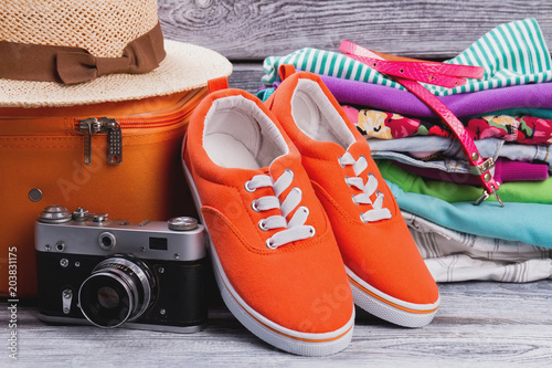 Woman clothes with suitcase and vintage photo camera. Close up red female sneakers.